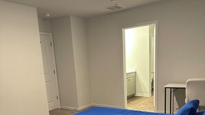 A bedroom with a large bed, a chair, and a door leading to another room. - Room with private bathroom for rent for long periods. (Pooler)