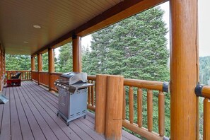 Eine überdachte Holzterrasse mit Grill und Gartenmöbeln.