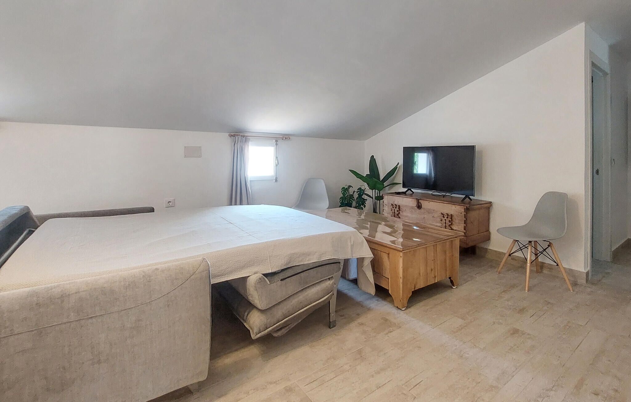 Habitació petita amb llit, escriptori de fusta, televisió i cadira.