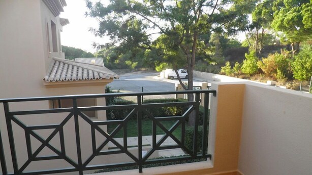 Un balcon doté d’un sol carrelé et d’une rambarde en métal noir.