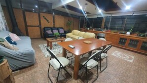 A cozy living room with a sofa, a dining table with chairs, and a kitchen area with cabinets and a countertop. - CASA EL CANELO (El Quisco)