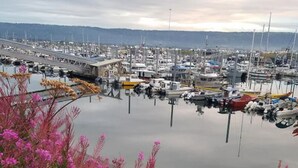 Un puerto deportivo con barcos amarrados, rodeado de plantas florecientes de color rosa.