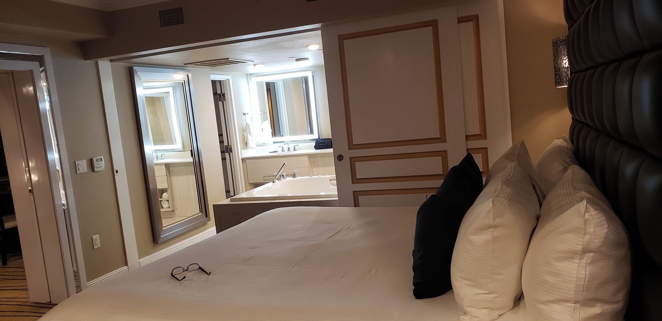 Camera d'albergo con un letto grande, uno specchio e bagno visibile tramite una porta aperta.
