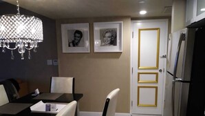 A dining area with a chandelier, a table with chairs, framed pictures on the wall, and a refrigerator. - Las Vegas Formula 1 Weekend Nov21 2025 (Las Vegas)