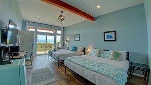 Un dormitorio con dos camas, un escritorio con ordenador y un ventanal con vistas.
