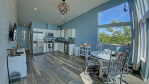 Una cocina amplia con armarios blancos, una isla central y un comedor con mesa y sillas.