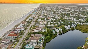 An aerial view of a coastal residential area with houses, a beach, and a body of water. - New Coastal Retreat | Spa & Pool + Beach Access (Destin)