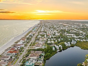 An aerial view of a coastal residential area with houses, a beach, and a body of water.
