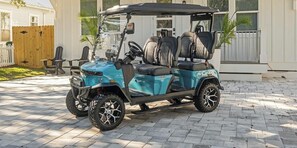 Une voiturette de golf est garée sur une allée pavée, avec une maison en arrière-plan.