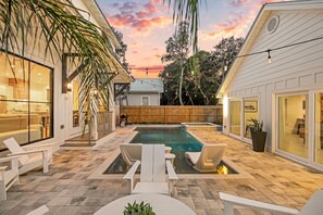 Un jardin avec une piscine, un espace salon extérieur et une clôture en bois.