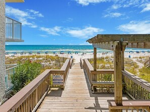 A wooden boardwalk leading to a beach with a clear sky.
