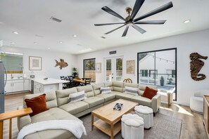 A modern living room with a sectional sofa, a coffee table, and a ceiling fan.