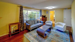 A living room with a sofa, armchairs, a coffee table, a wooden side table, and a patterned rug. - Lehr Court Cottage - Home in the Heart of Wooster (Wooster)