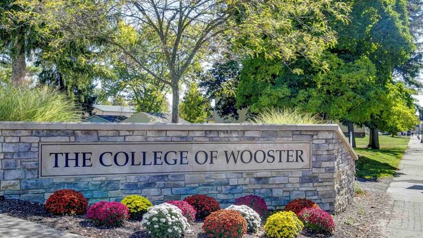 A stone sign with "The College of Wooster" written on it, surrounded by colorful flower beds. - Lehr Court Cottage - Home in the Heart of Wooster (Wooster)