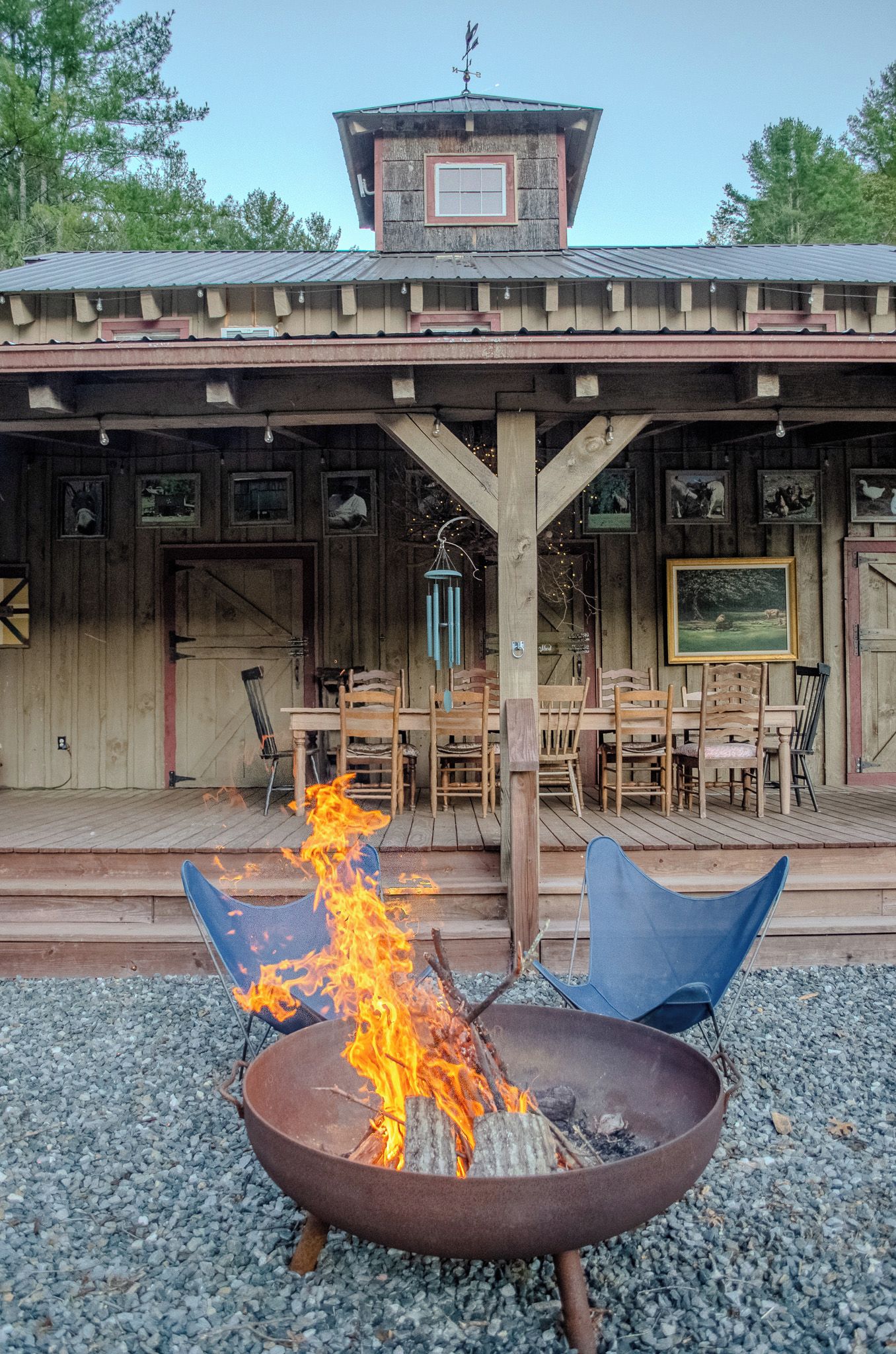 A rustic outdoor seating area with a fire pit, wooden tables, and chairs.