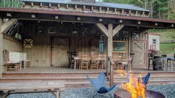 A rustic wooden building with a covered porch, outdoor seating, and a fire pit.