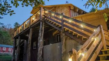 A wooden cabin with a wooden staircase leading to a balcony.