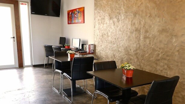 A conference room with a large table, black chairs, a TV, and a painting on the wall. - Lost & Found Hostel & Suites (Albufeira)