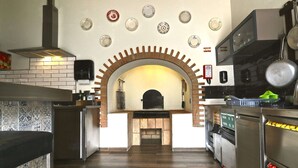 A kitchen with a brick fireplace, modern appliances, and a tiled backsplash. - Lost & Found Hostel & Suites (Albufeira)