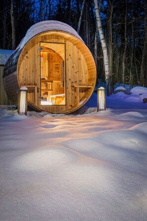A wooden cabin with an open door, surrounded by snow, and a forest in the background. - Nature Retreat, Sauna, Hot Tub, Gameroom, Fire Pit (Woodstock)