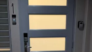 Una porta grigia dal design moderno, dotata di serratura digitale e maniglia.