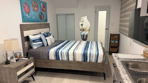 Una camera da letto moderna con un letto, un comodino, una lampada e un quadro appeso al muro.