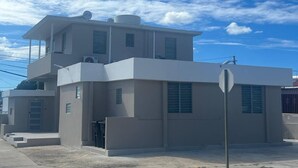A modern two-story building with a flat roof, large windows, and a visible satellite dish.
