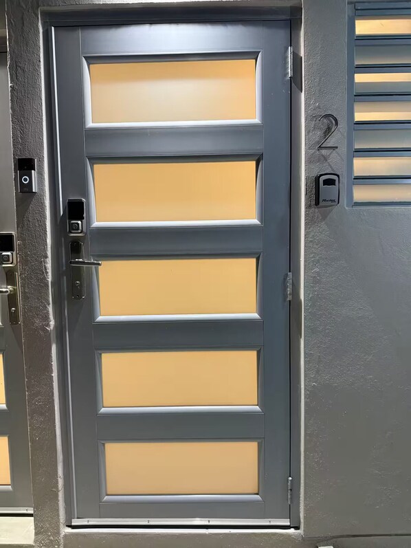 A gray door with a keypad lock and a number 2 on the wall beside it.