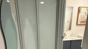 A modern bathroom with a glass shower enclosure, a sink with a mirror, and a toilet. - A&E L.A. Rental Apartments #2 (Carolina)