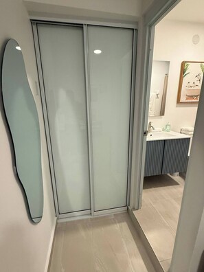 A modern bathroom with a glass shower enclosure, a sink with a mirror, and a toilet. - A&E L.A. Rental Apartments #2 (Carolina)
