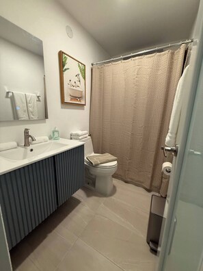 A bathroom with a sink, toilet, and shower curtain.