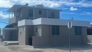A modern two-story building with a flat roof, multiple windows, and a visible satellite dish. - A&E L.A. Rental Apartments #6 (Carolina)