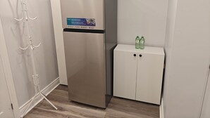 A stainless steel refrigerator with a full drawer access label, a white cabinet with two doors, and a coat rack with hooks.