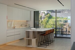 Una cocina moderna con una isla central, taburetes de bar y un ventanal con vistas a un paisaje rocoso.