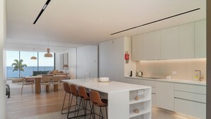 A modern kitchen with a large island, bar stools, and a view of the sea. - Savoy Monumentalis VII – Comfort & Luxury (Funchal)