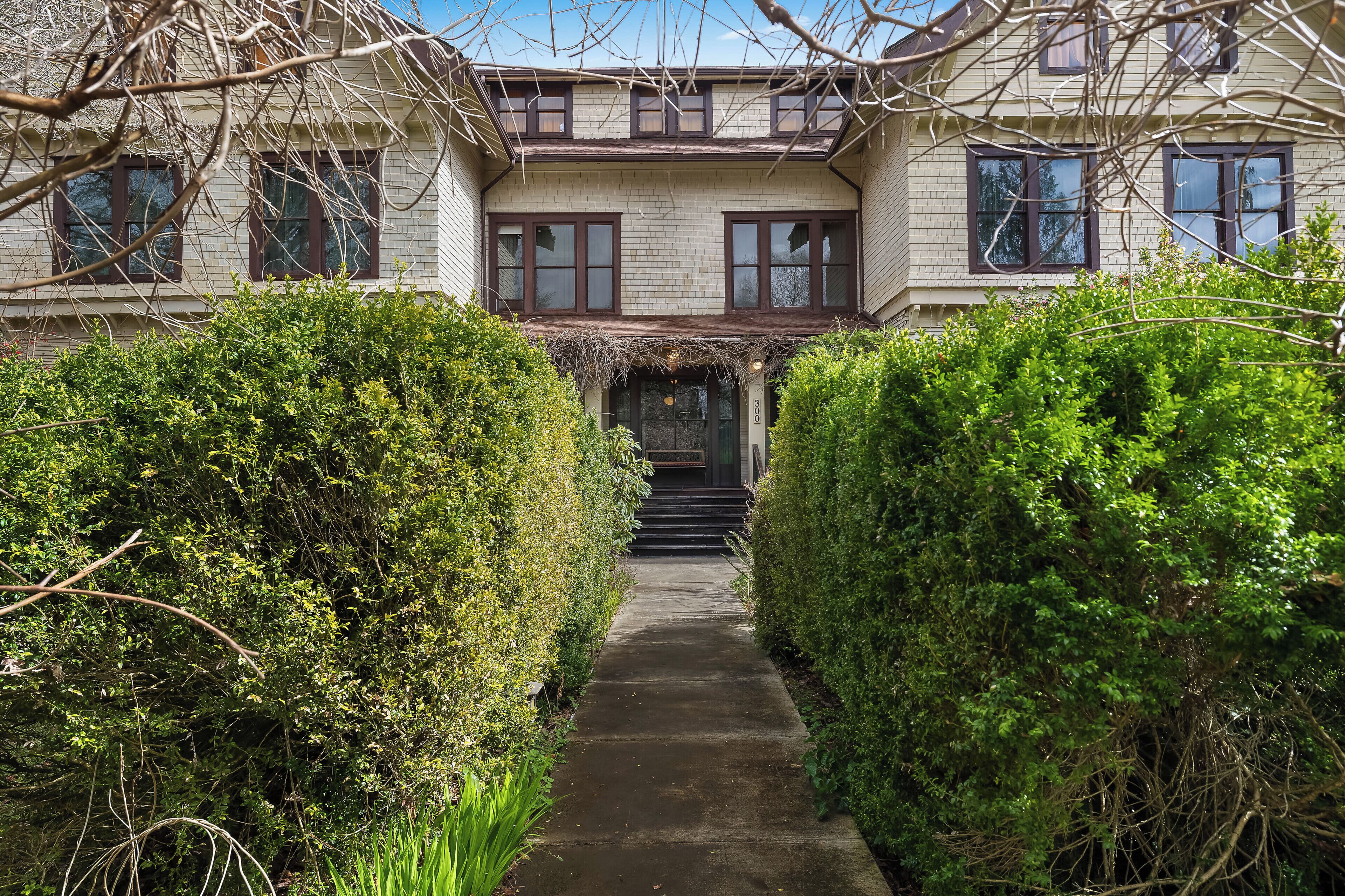 A two-story house with a covered entrance, a pathway leading to the front door, and a well-maintained garden.