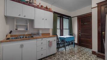Una cocina con encimera de madera, armarios blancos, un lavabo y una mesa de comedor con sillas.