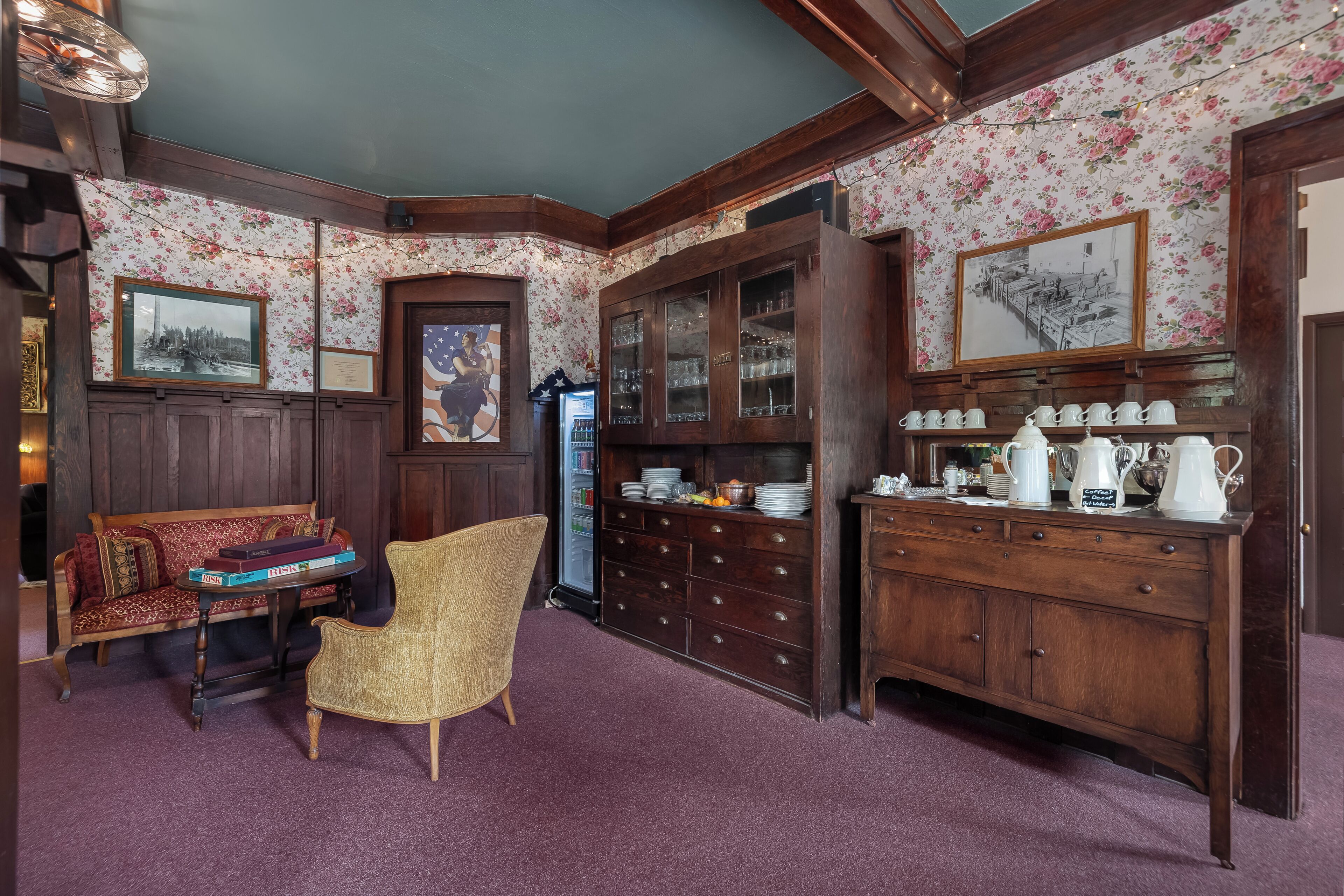 A room with a wooden bench, a wicker chair, a cabinet with glass doors, and a refrigerator.