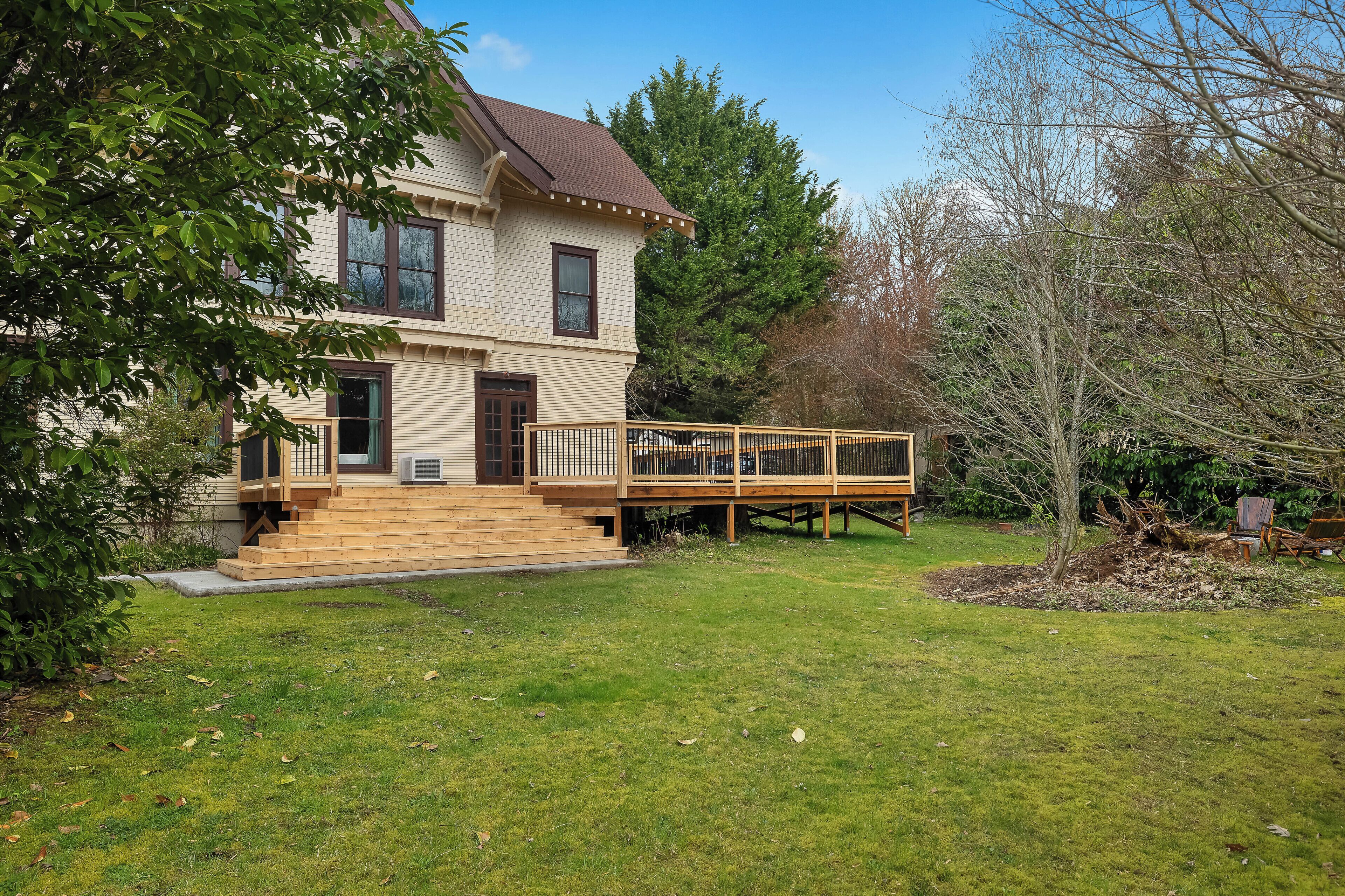 A two-story house with a deck, a front porch, and a well-maintained lawn.