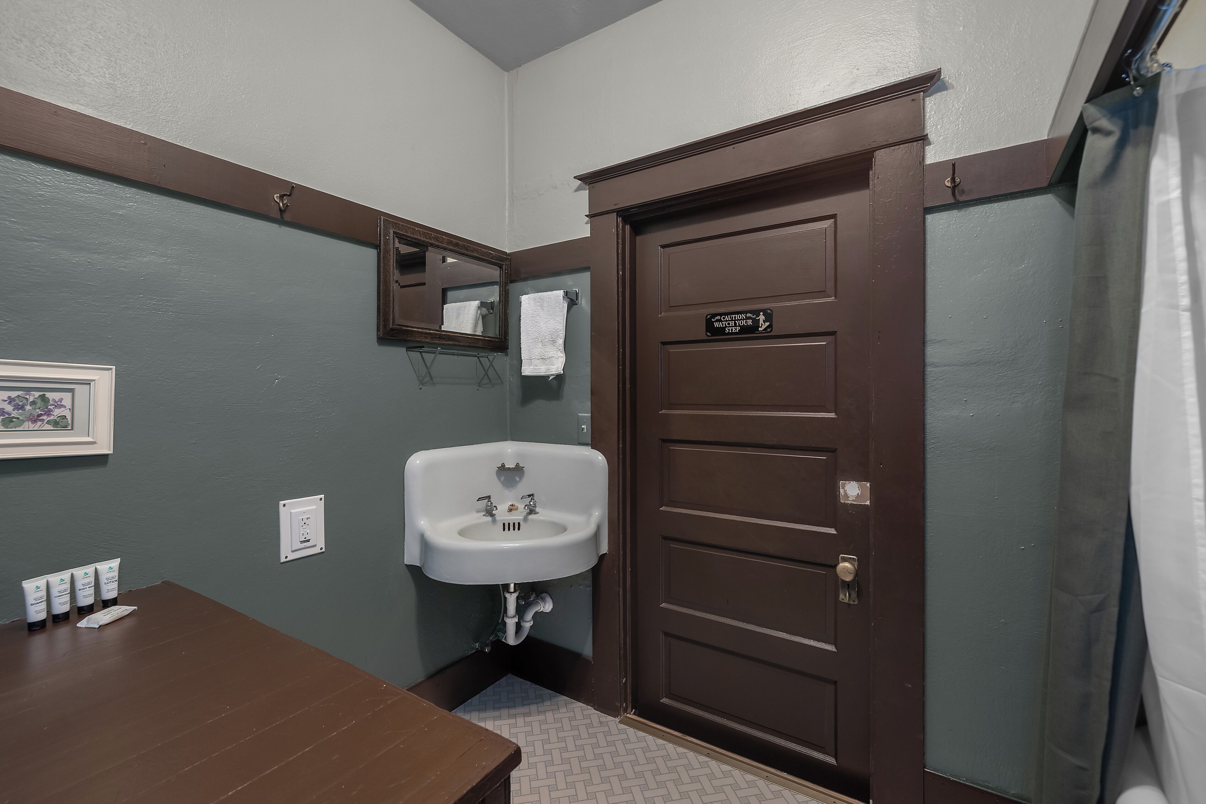 A bathroom with a sink, mirror, and a door marked 'Center Restroom Step.'