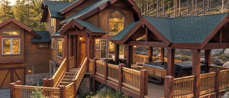 A wooden cabin with a deck, stairs, and a covered outdoor seating area.