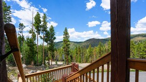 A wooden deck with a view of a forest and mountains. - Moonstone Lodge • Hot Tub • Spacious (Breckenridge)
