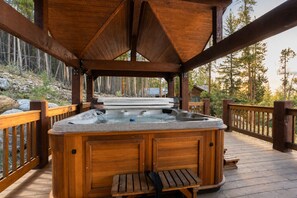 A wooden deck with a hot tub, surrounded by a wooden deck and a wooden railing.