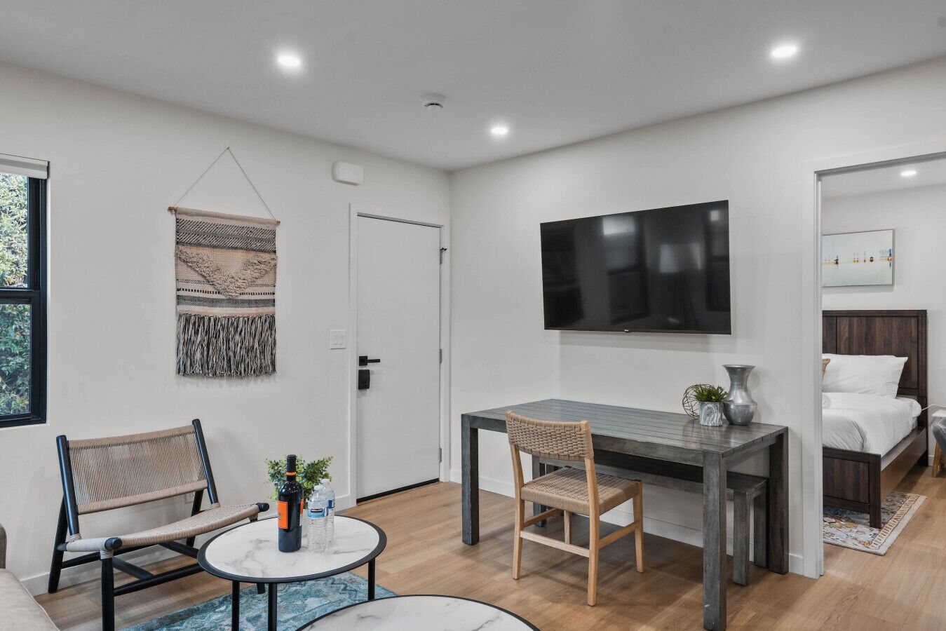 A modern room with a bed, a desk with a chair, a TV, and a window.