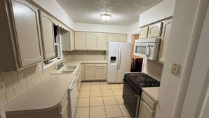 A compact kitchen with white cabinets, a refrigerator, a microwave, and a stove. - Charming SE ICT Home 3 Bedrooms/2 Baths/2 Queens/1 Twin/1 Queen Pullout (Wichita)