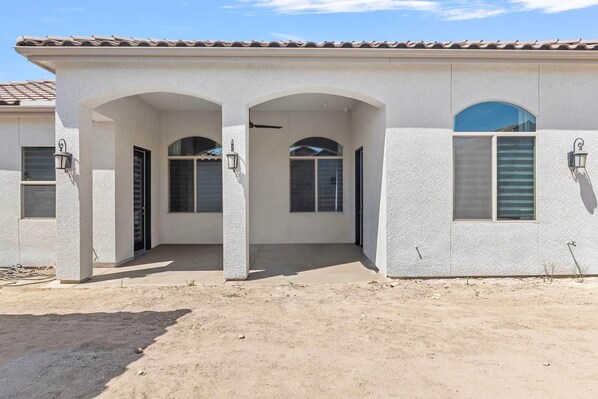 A two-story house with a covered front porch, arched doorways, and a tiled roof. - The Executive Retreat at Westberry (Madera)