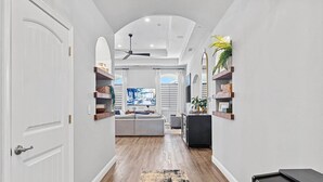 A hallway with a sofa, a TV, and shelves with decorative items. - The Executive Retreat at Westberry (Madera)