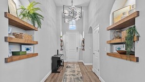 A hallway with wooden shelves on either side, a patterned rug, and a door at the end. - The Executive Retreat at Westberry (Madera)