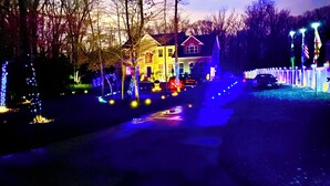 A house with a well-lit driveway and a fence.
