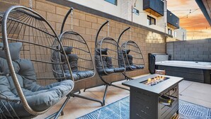 A modern outdoor seating area with cushioned chairs and a fire pit table. - Oasis at Pecan Valley l Resort Access Included (Hurricane)